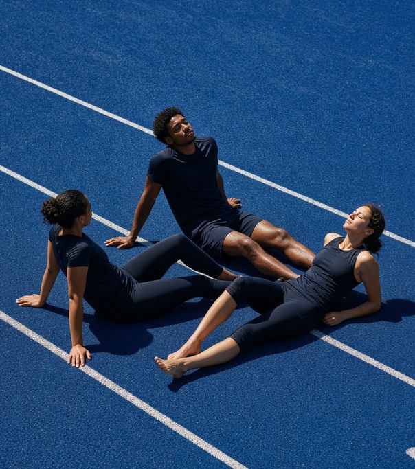Three runners resting on a blue track
